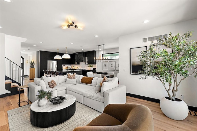 living area featuring recessed lighting, light wood finished floors, and stairs