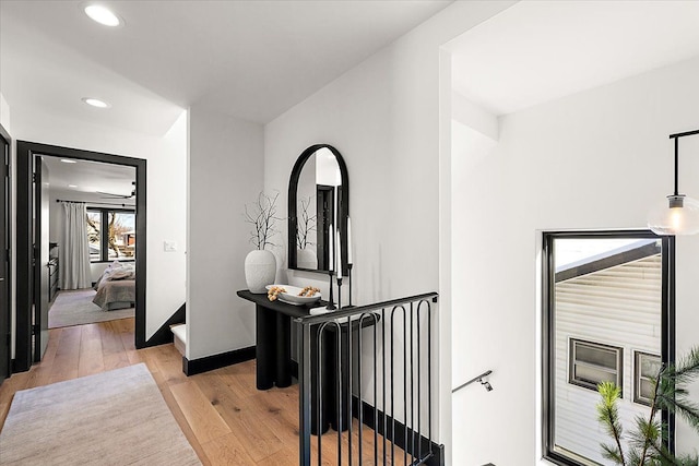 hallway featuring an upstairs landing, recessed lighting, baseboards, and light wood finished floors