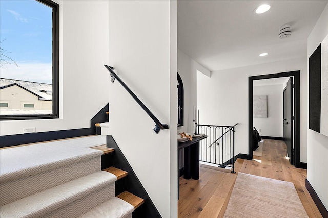 staircase featuring baseboards, wood finished floors, and recessed lighting