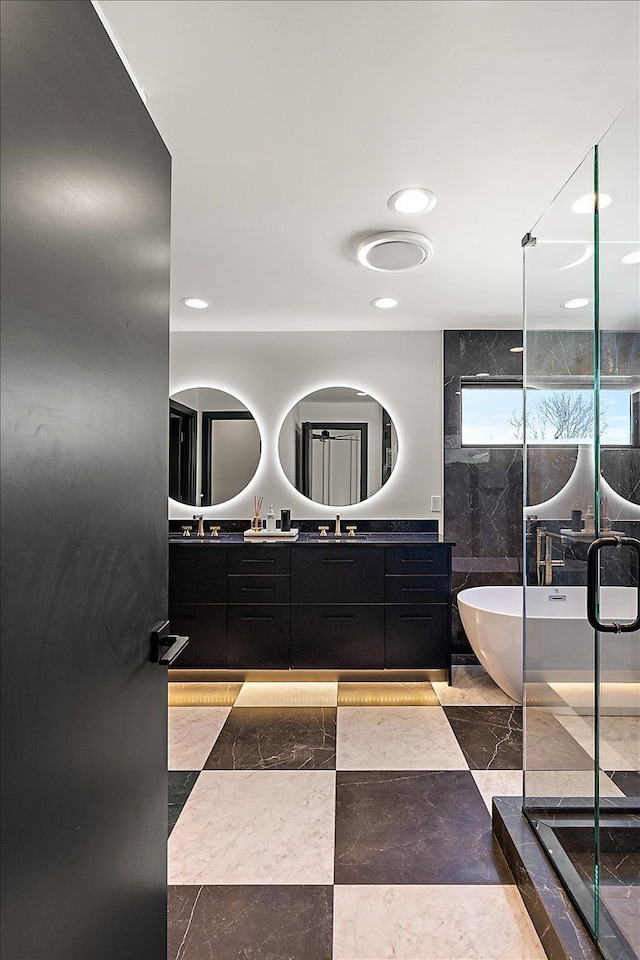 full bath featuring double vanity, recessed lighting, a freestanding bath, a stall shower, and a sink