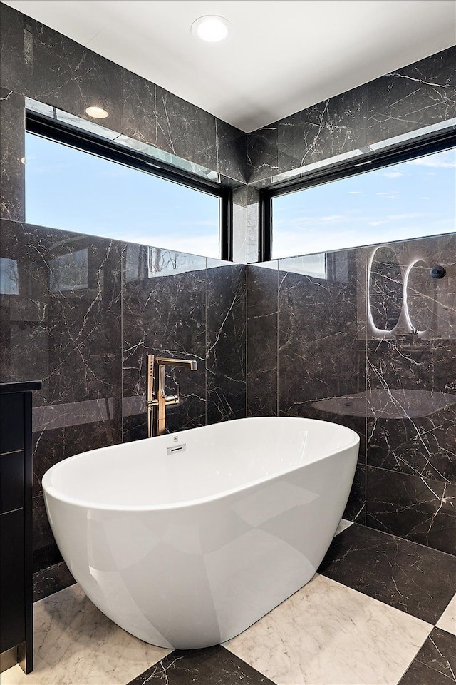 bathroom featuring recessed lighting, marble finish floor, and a freestanding tub