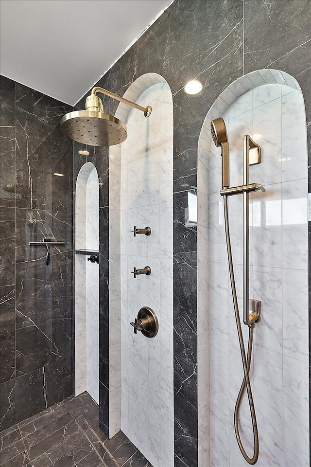 full bath featuring marble finish floor and tiled shower