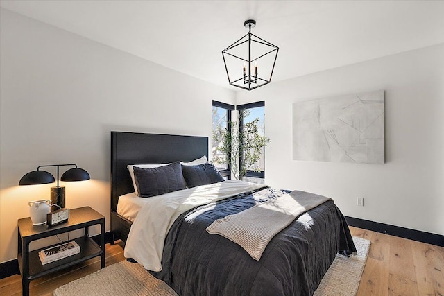 bedroom featuring light wood-style flooring, baseboards, and a notable chandelier