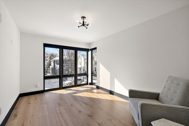 unfurnished room featuring an inviting chandelier, baseboards, and wood finished floors