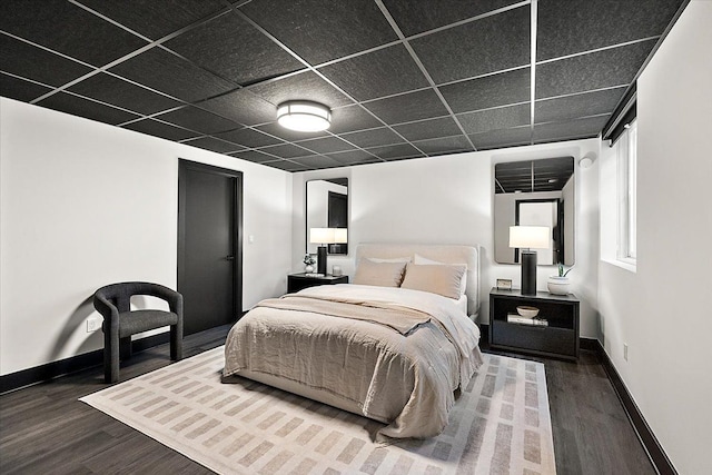 bedroom with baseboards, dark wood finished floors, and a drop ceiling