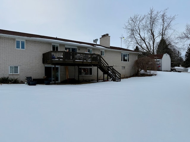 snow covered back of property with a wooden deck