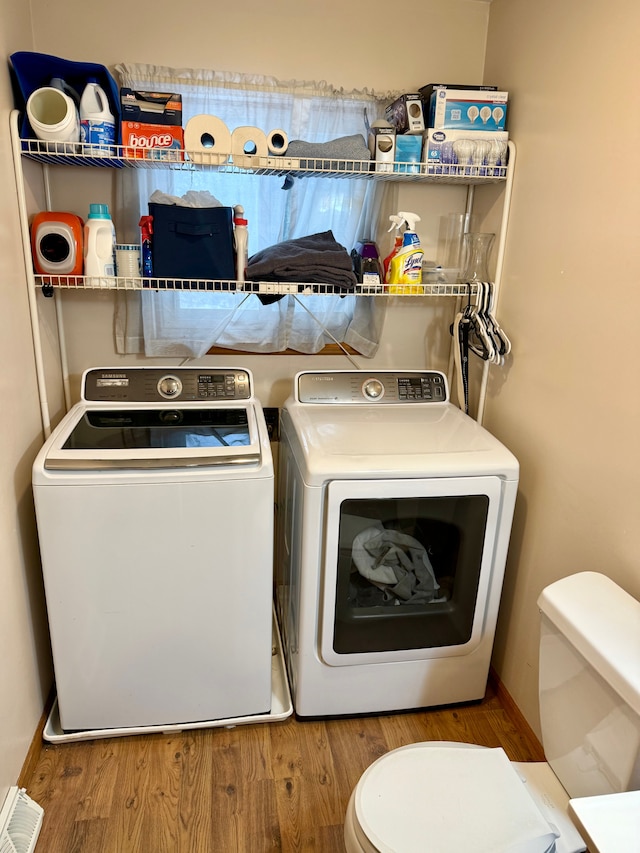 washroom with wood-type flooring and washer and dryer