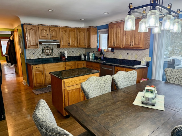 kitchen featuring dark wood-type flooring, tasteful backsplash, decorative light fixtures, and a kitchen island