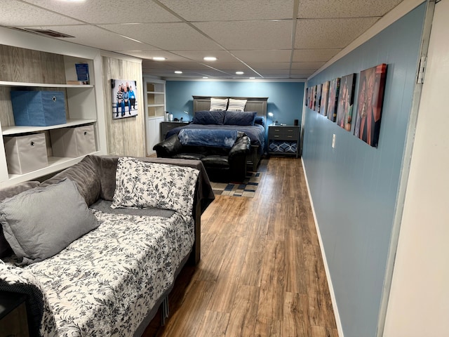 bedroom featuring wood-type flooring and a drop ceiling