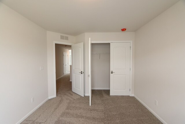 unfurnished bedroom featuring a closet, baseboards, carpet flooring, and visible vents