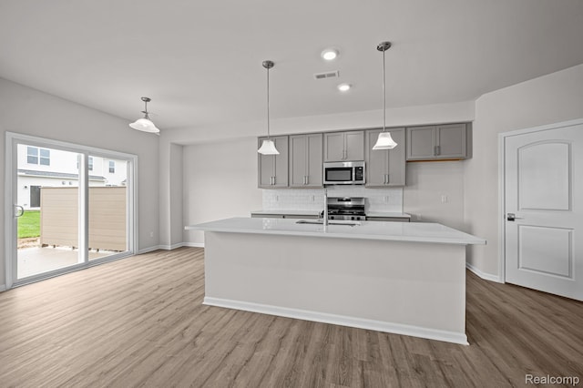 2302 Mill Ln, Saline, MI 48176 - kitchen with appliances with stainless steel finishes, gray cabinetry, wood finished floors, decorative backsplash, and recessed lighting
