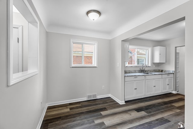 kitchen with white cabinetry, light stone countertops, sink, and dark hardwood / wood-style floors