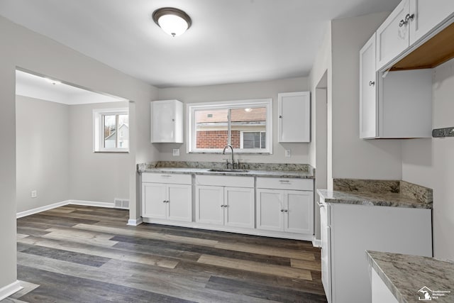 kitchen featuring white cabinetry, dark hardwood / wood-style floors, light stone countertops, and sink