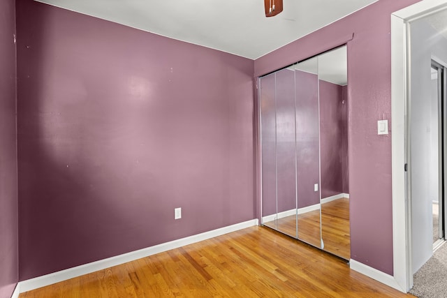 unfurnished bedroom with wood-type flooring, ceiling fan, and a closet