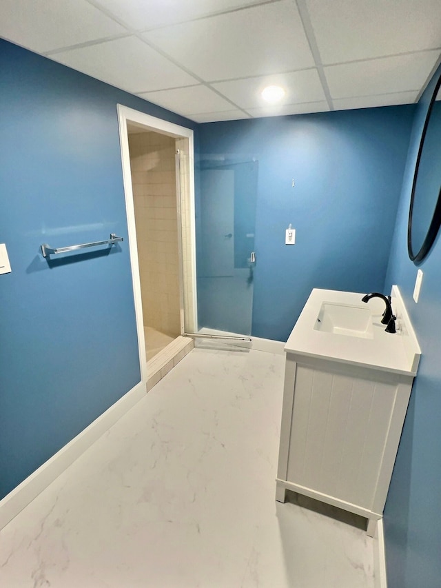 bathroom with a paneled ceiling, vanity, and a shower