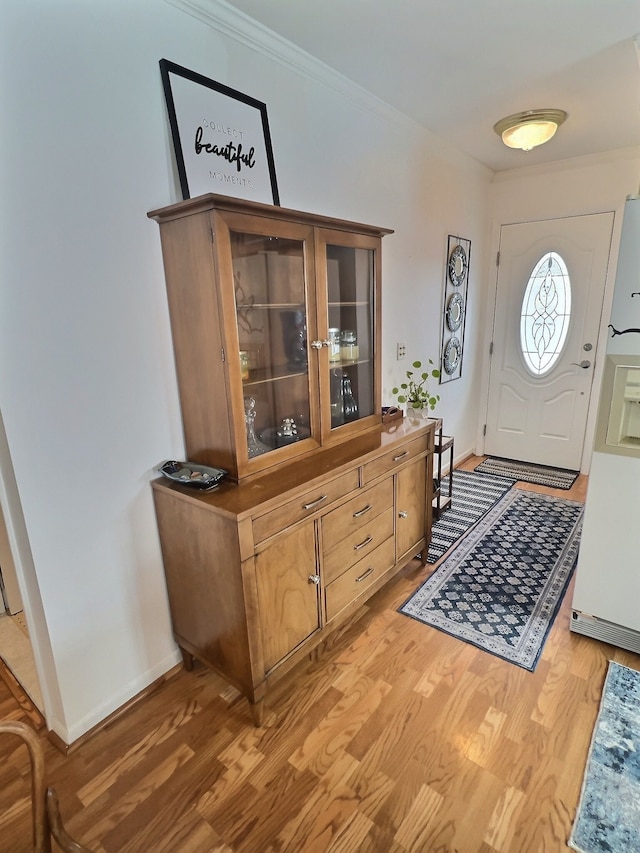 entryway with hardwood / wood-style flooring and crown molding