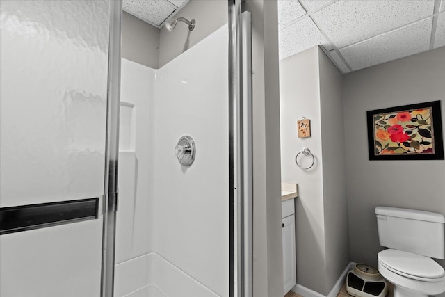 bathroom with a shower, toilet, a drop ceiling, and vanity