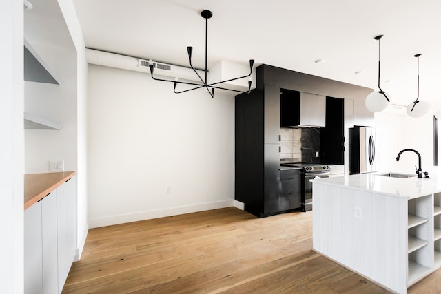 kitchen featuring appliances with stainless steel finishes, tasteful backsplash, sink, hanging light fixtures, and light wood-type flooring