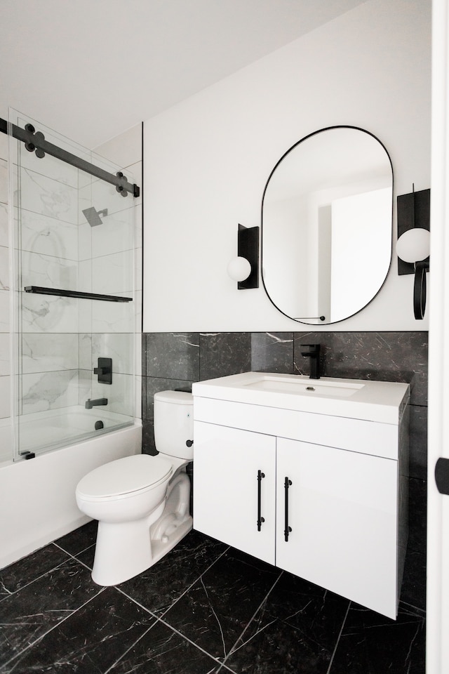 full bathroom with tile walls, vanity, toilet, and tiled shower / bath