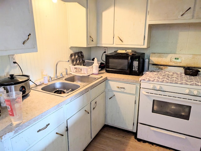 kitchen featuring white cabinetry, white gas range, sink, and hardwood / wood-style floors