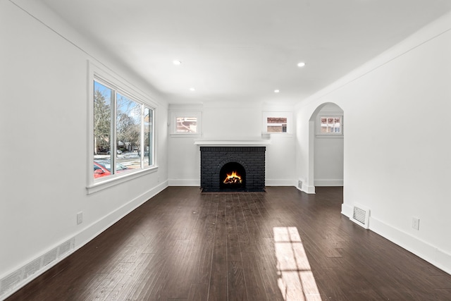 unfurnished living room with dark hardwood / wood-style flooring and a brick fireplace