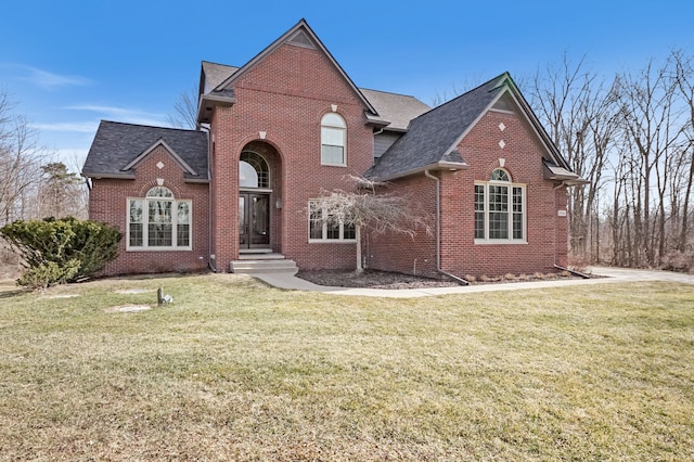 traditional-style house with a front yard, brick siding, and a shingled roof