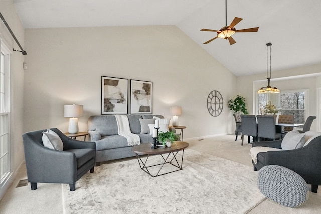 living area featuring baseboards, ceiling fan, high vaulted ceiling, and carpet