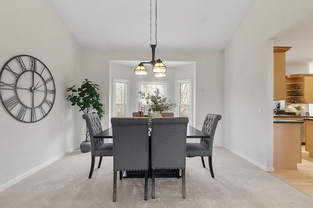 dining space with baseboards and light colored carpet