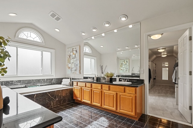 bathroom featuring visible vents, a garden tub, a sink, tile patterned flooring, and lofted ceiling