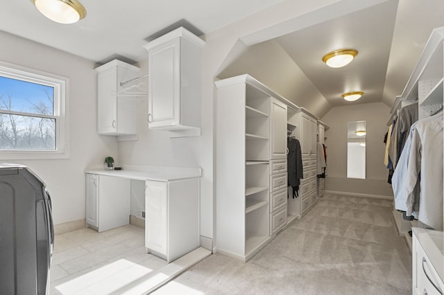 walk in closet featuring light colored carpet, washer / dryer, and vaulted ceiling