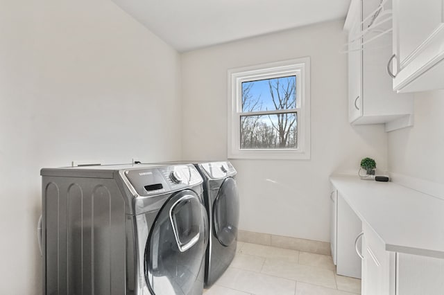 laundry area with baseboards, cabinet space, light tile patterned flooring, and washer and clothes dryer