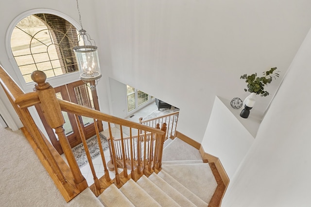 stairs featuring a high ceiling, baseboards, and carpet floors