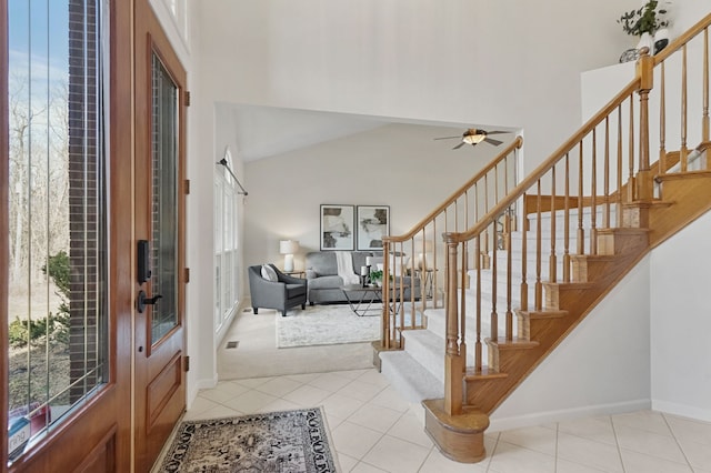 tiled entryway featuring visible vents, baseboards, stairs, lofted ceiling, and a ceiling fan