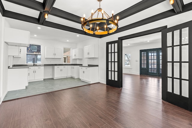 kitchen with dark wood-type flooring, white cabinetry, hanging light fixtures, french doors, and beamed ceiling