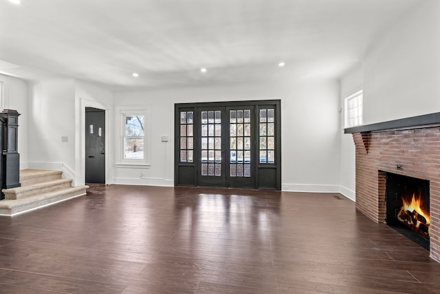 unfurnished living room featuring french doors, a fireplace, and dark wood-type flooring