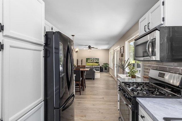 kitchen featuring ceiling fan, appliances with stainless steel finishes, tasteful backsplash, light hardwood / wood-style floors, and white cabinets