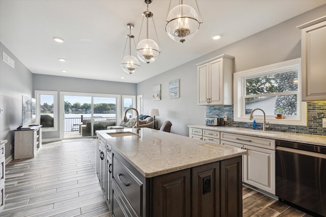 kitchen featuring sink, tasteful backsplash, hanging light fixtures, a center island with sink, and dishwashing machine