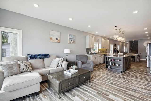 living room with light hardwood / wood-style flooring, sink, a notable chandelier, and plenty of natural light