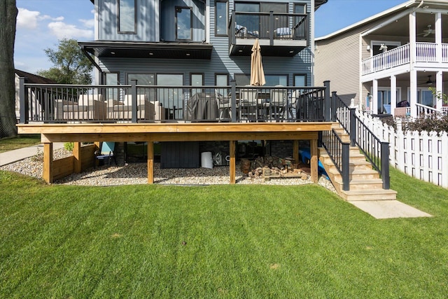 rear view of property with a wooden deck and a lawn