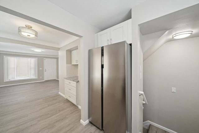 kitchen featuring white cabinets, light stone counters, stainless steel fridge, and light hardwood / wood-style floors