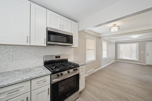 kitchen featuring light hardwood / wood-style flooring, white cabinetry, backsplash, stainless steel appliances, and light stone countertops