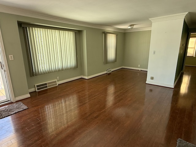 unfurnished room with baseboards, dark wood finished floors, visible vents, and crown molding