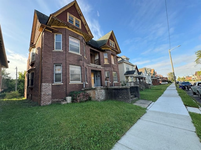 view of front of property featuring a front yard, a residential view, and brick siding