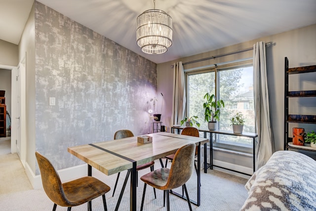 dining space featuring an accent wall, light carpet, a notable chandelier, and baseboards