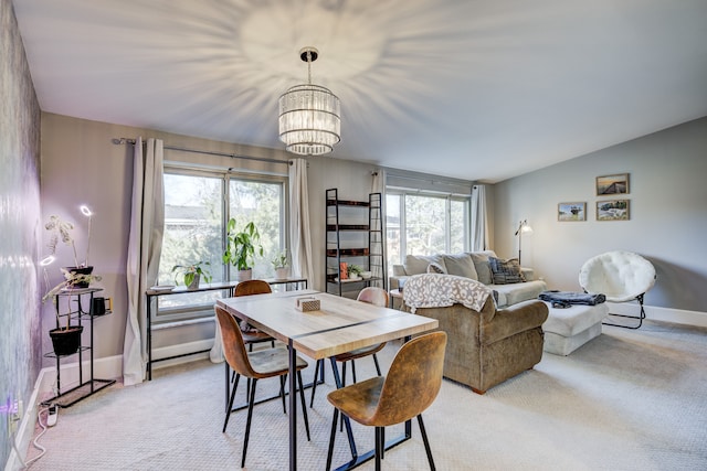 dining area featuring light carpet, an inviting chandelier, lofted ceiling, and baseboards