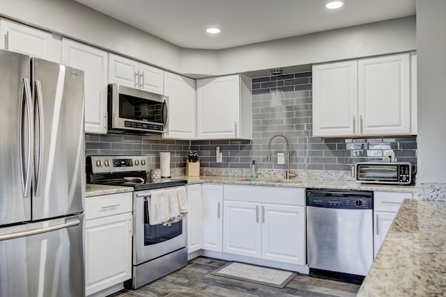 kitchen featuring stainless steel appliances, dark wood-type flooring, a sink, white cabinetry, and tasteful backsplash