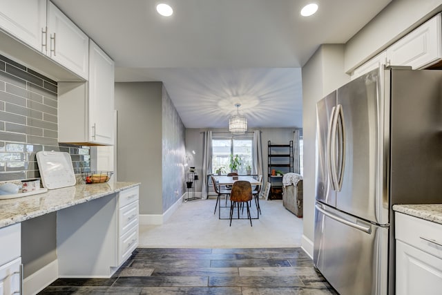 kitchen with white cabinets, dark wood-style floors, freestanding refrigerator, light stone countertops, and backsplash