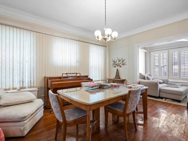 dining area featuring crown molding, dark wood-type flooring, and a chandelier