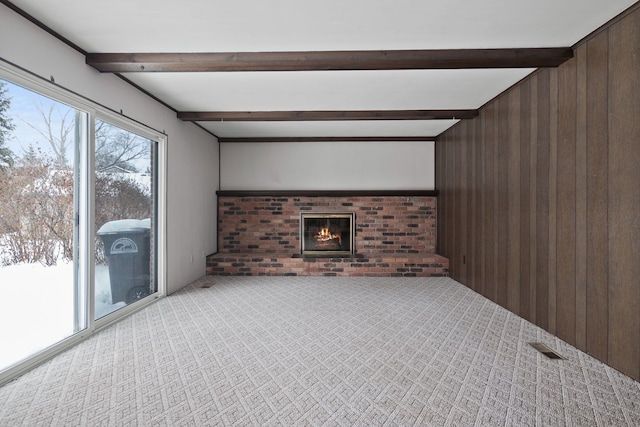 unfurnished living room featuring a fireplace, beamed ceiling, and wooden walls