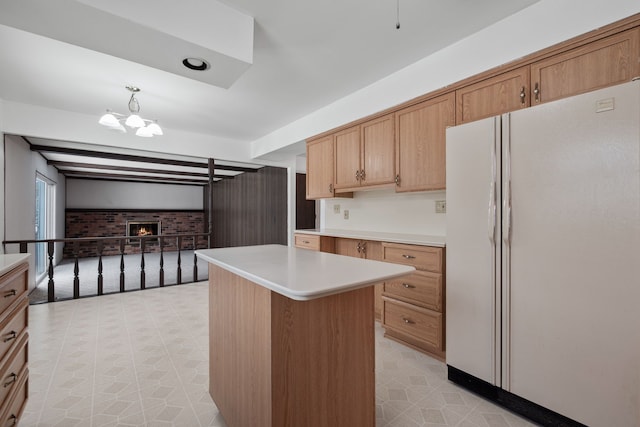 kitchen featuring a chandelier, a center island, pendant lighting, white refrigerator, and a fireplace